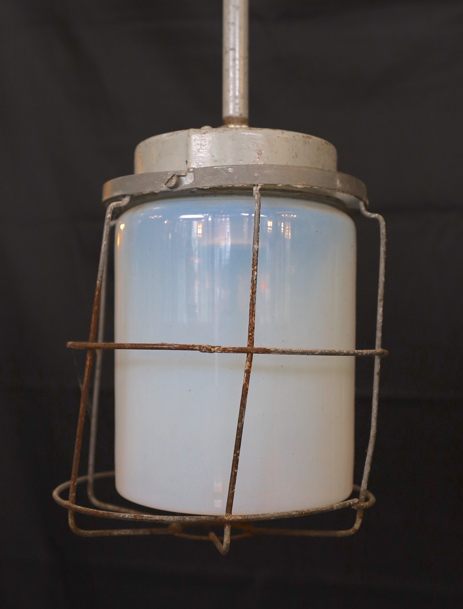 A pair of Czechoslovakian painted alloy industrial ceiling lights with caged Vaseline glass shades, height 74cm. width 21cm